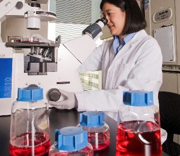 Female researcher in lab looking through microscope